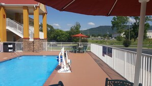 Ein Poolbereich mit Rettungsschwimmerstand, überdachten Sitzmöglichkeiten und Blick auf die umliegende Landschaft.