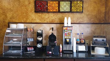 A kitchen counter with a waffle maker, coffee machine, and various condiments.