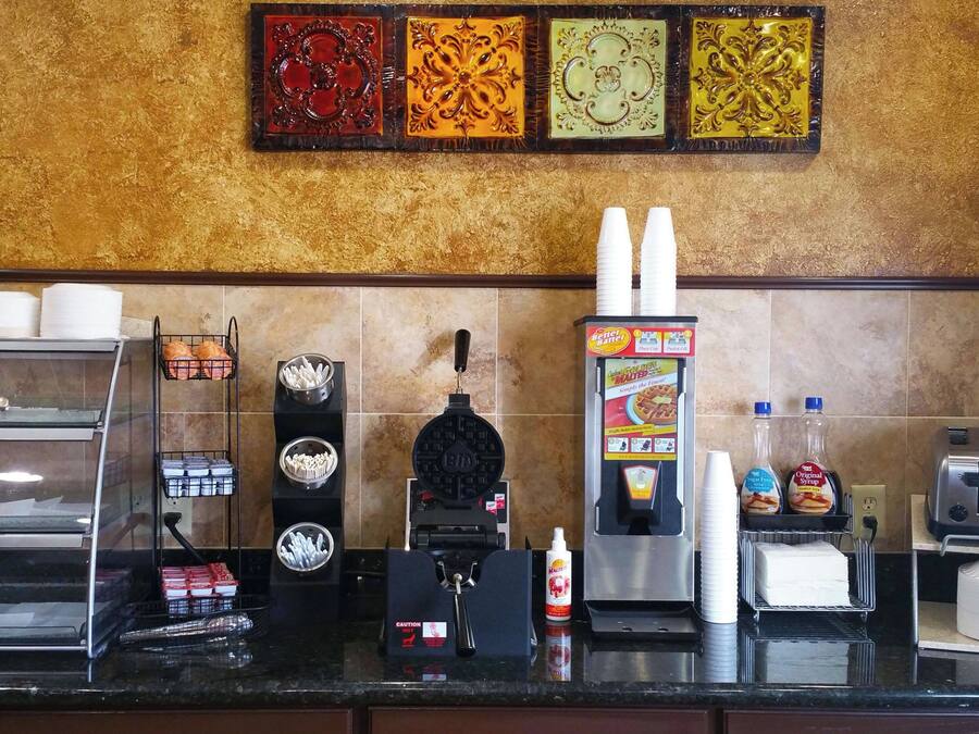 A kitchen counter with a waffle maker, coffee machine, and various condiments.