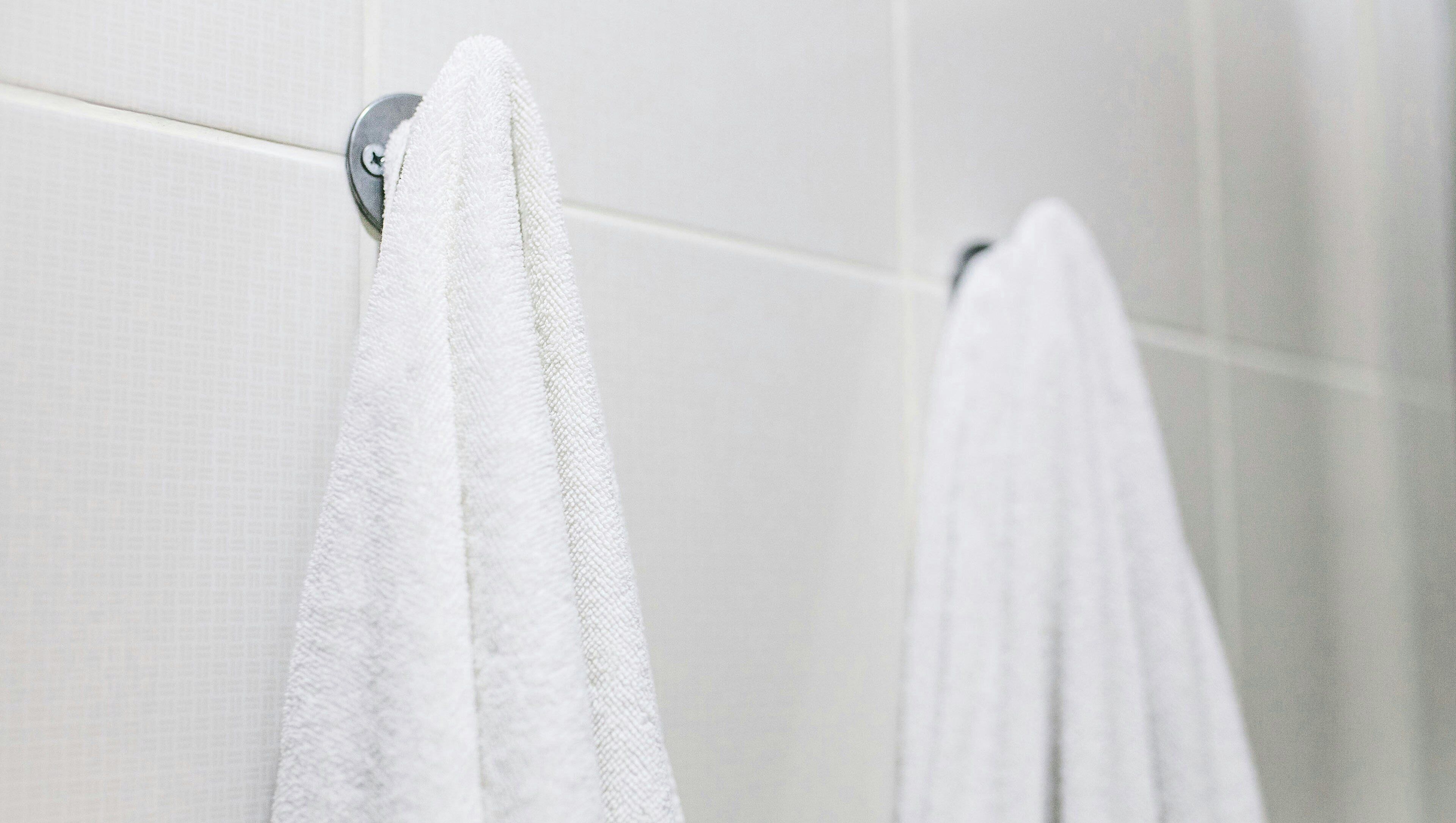 A bathroom with white tiled walls and a towel rack.