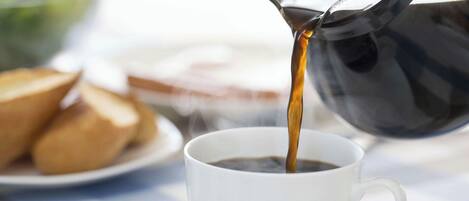 Café sendo servido de uma cafeteira preta.