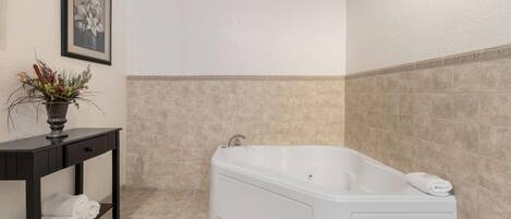 Un baño moderno con una bañera independiente, un tocador de madera oscura con un florero y un cuadro en la pared.