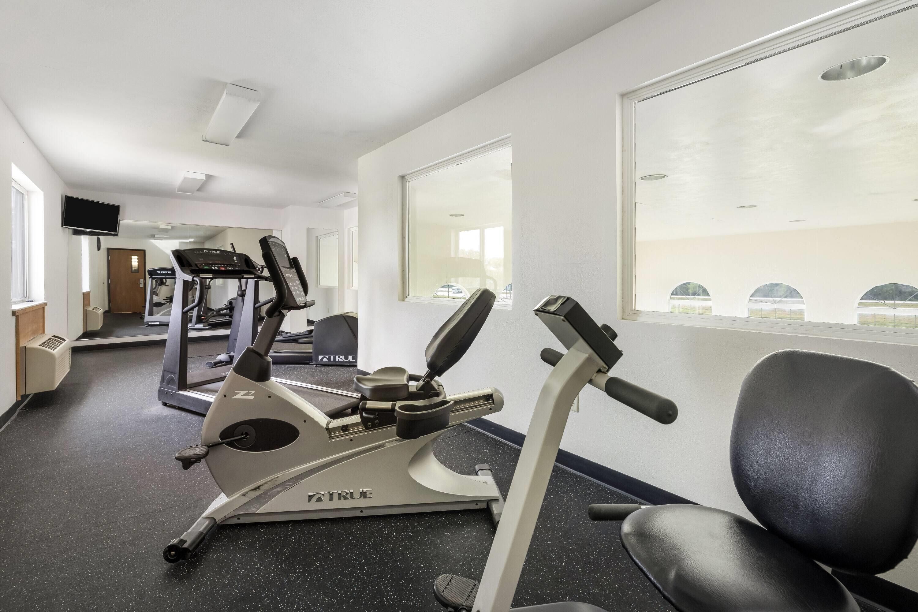 Un gimnasio con cintas de correr, bicicletas estáticas y equipo de ejercicio.