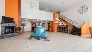 Eine geräumige Lobby mit Kamin, einem blauen Sofa, einer Treppe und einer Wanduhr.