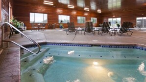 An indoor pool area with a wooden floor, tiled pool edge, and multiple lounge chairs and tables. - Best Western Plus Vintage Valley Inn (Zillah)