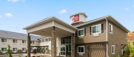 A hotel with a covered entrance, multiple windows, and a parking lot.