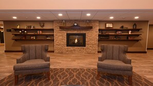 A lobby with a fireplace, two armchairs, and shelves with books and decorative items. - Best Western Plus Vintage Valley Inn (Zillah)