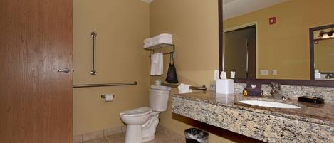 A bathroom with a toilet, sink, mirror, towel rack, and trash bin.