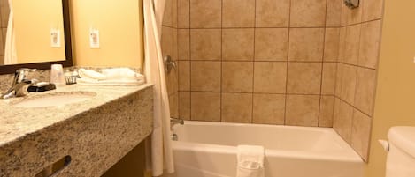 A bathroom with a sink, mirror, toilet, bathtub, and shower curtain.