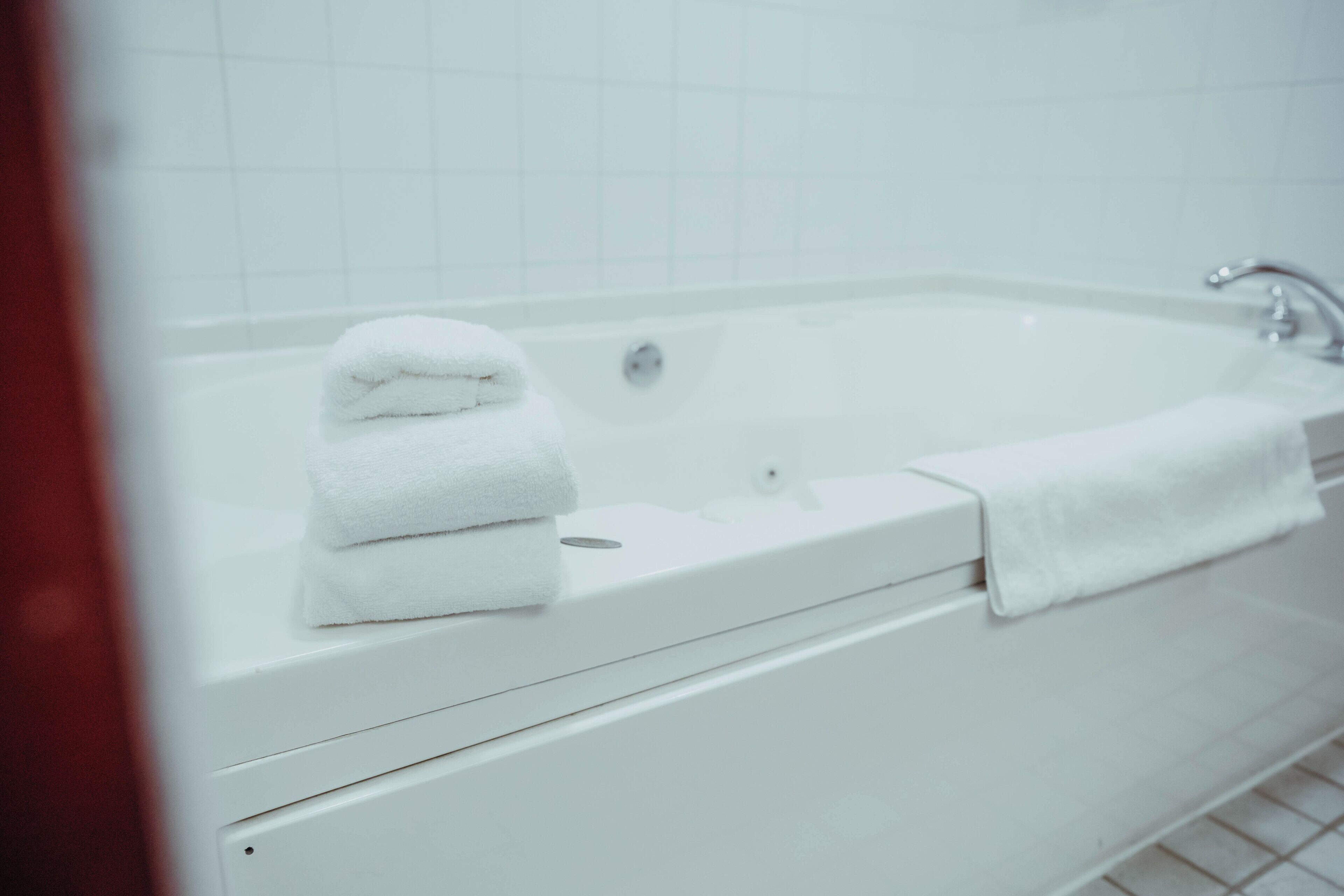 A white bathtub with a towel on the side.