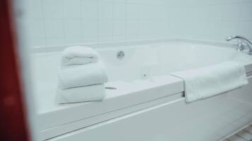Eine weiße Badewanne mit einem Handtuch daneben.