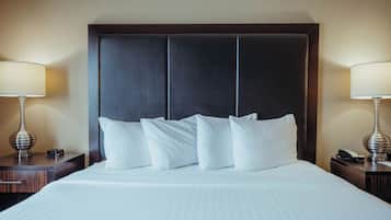 A hotel room with a large bed, a dark headboard, and two bedside lamps.