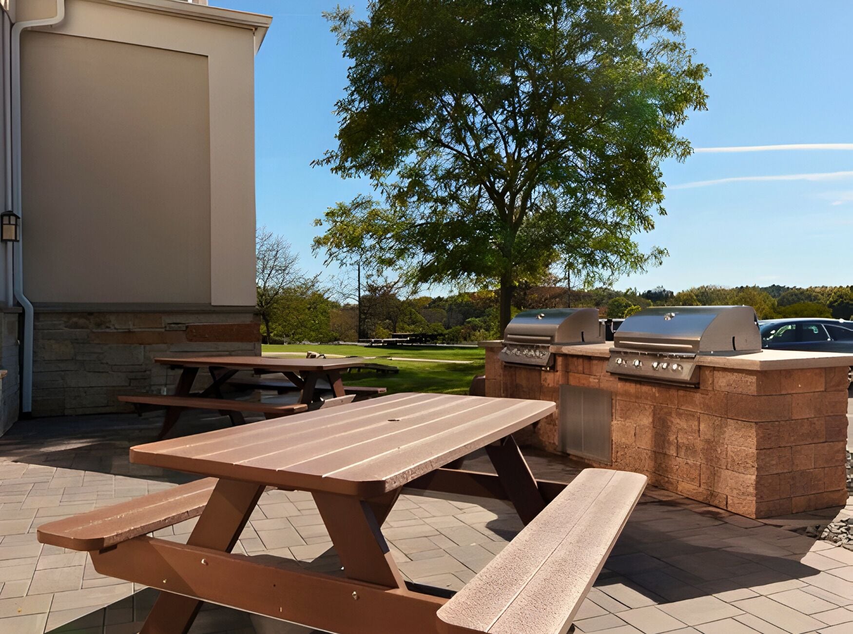 An outdoor patio with picnic tables and a barbecue grill.