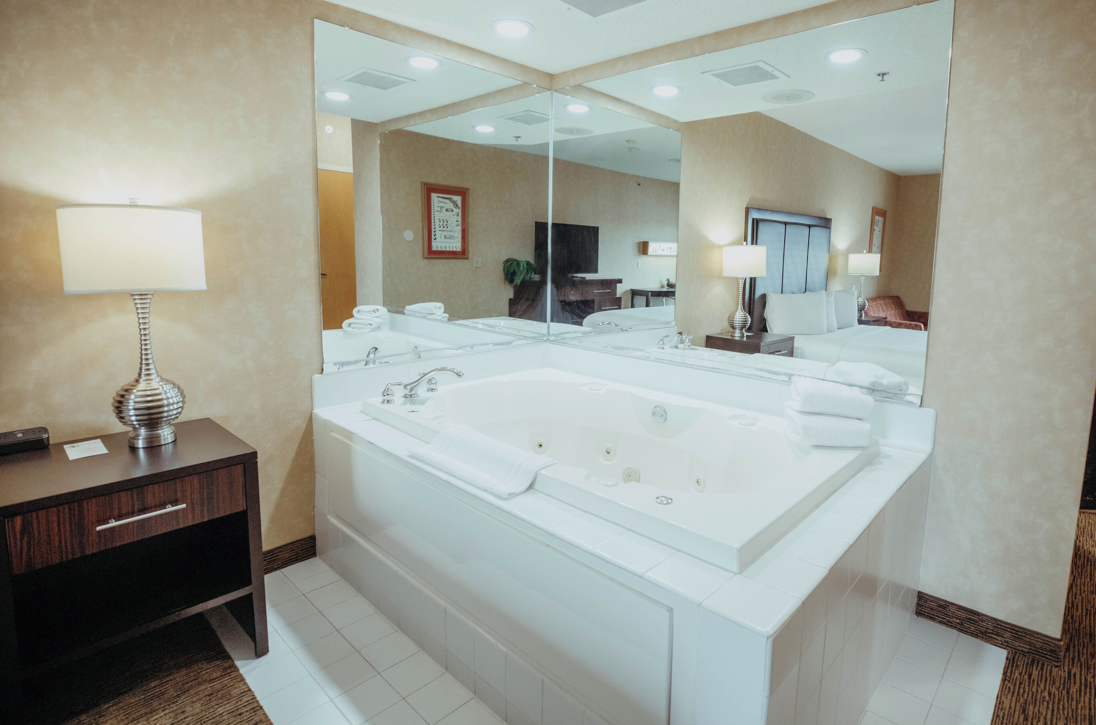 Une salle de bain moderne avec un grand miroir, une baignoire, un meuble-lavabo avec une lampe et un porte-serviettes.