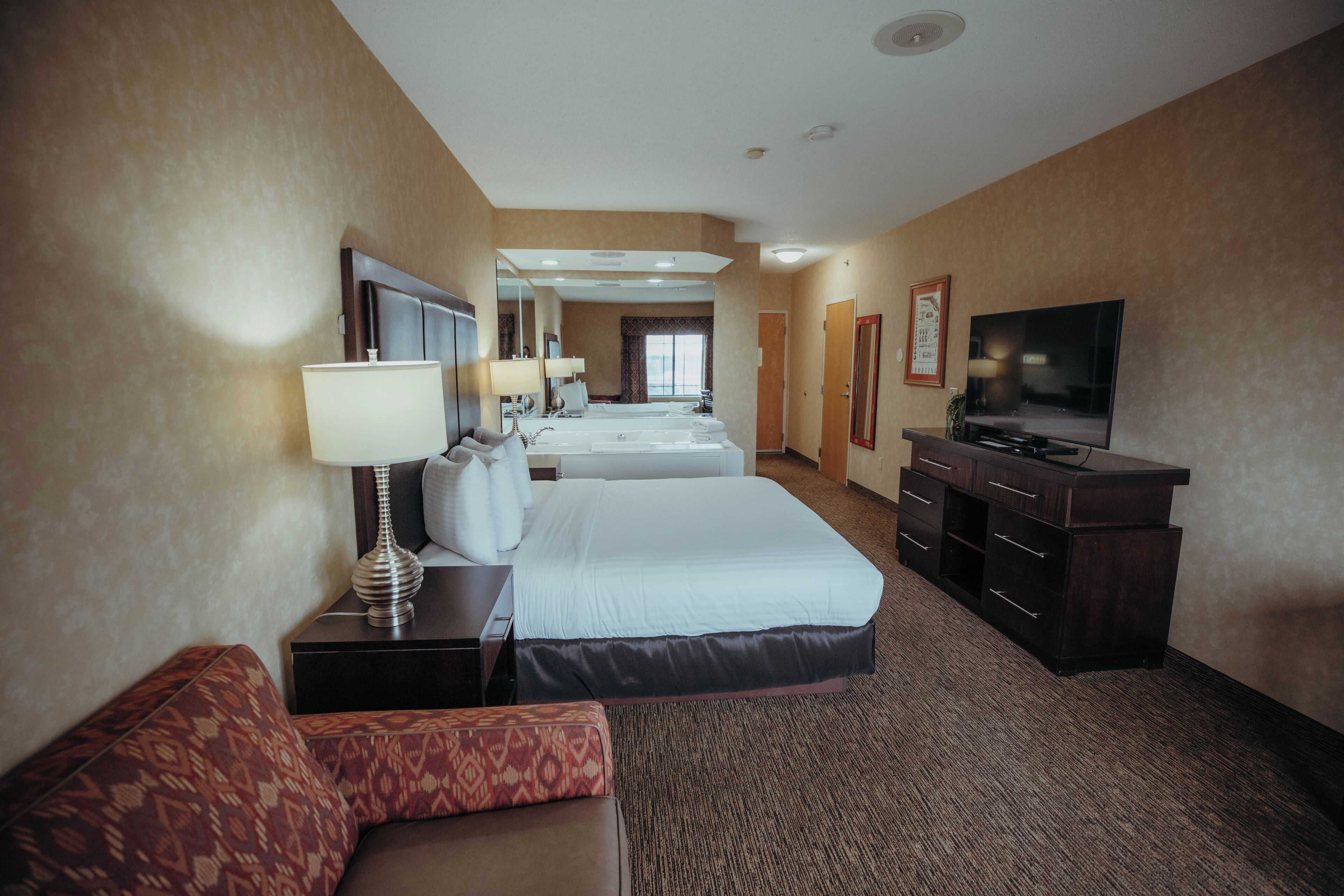 A hotel room with a bed, a TV, a desk, and a couch.