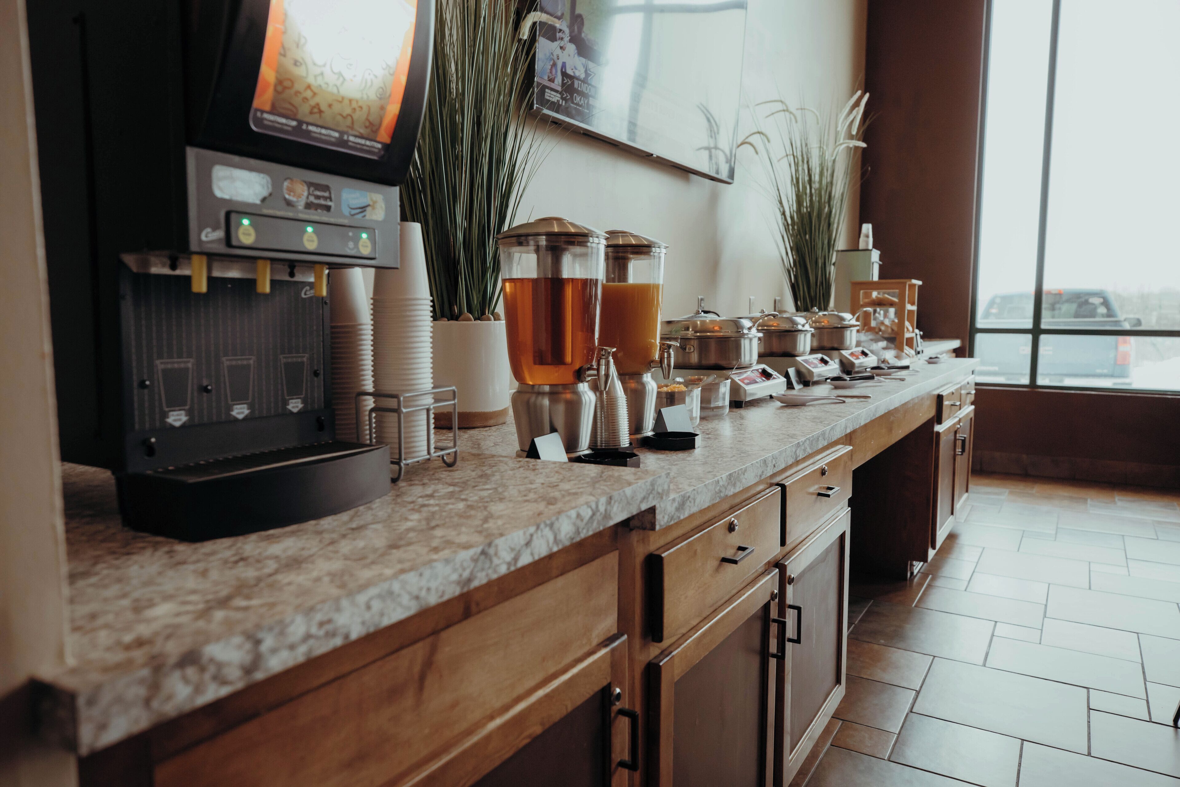 A breakfast bar with a coffee machine, tea dispensers, and various food items.