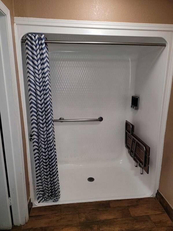 Une salle de bain équipée d’une douche, d’un porte-serviettes et d’un sèche-mains.