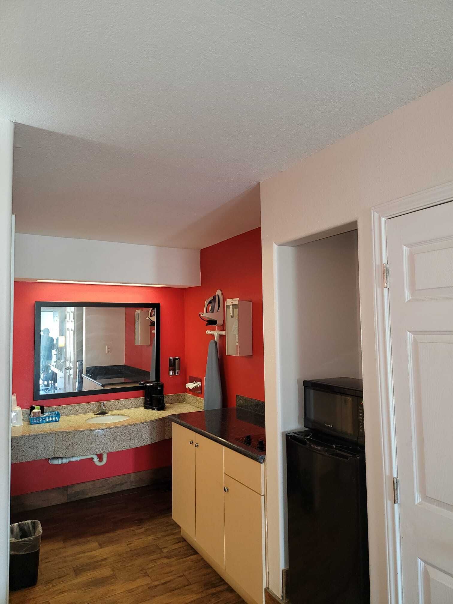 A compact kitchen with a red wall, a microwave, a stove, and a sink.