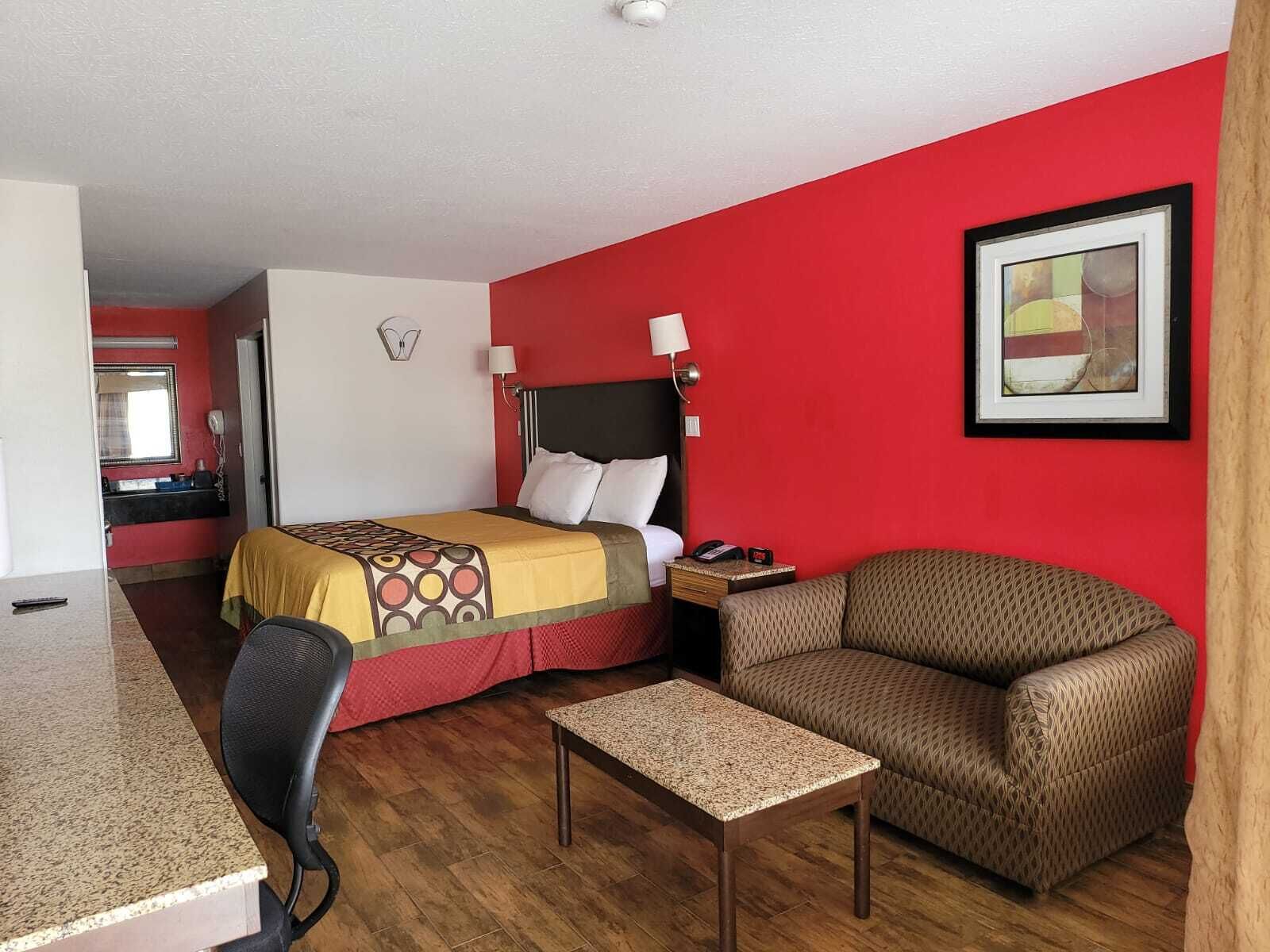 A hotel room with a bed, a desk, a chair, and a small table.