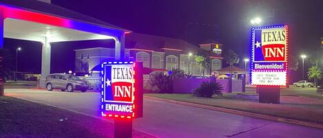 A Texas Inn sign at night with illuminated entrance and welcome signs.