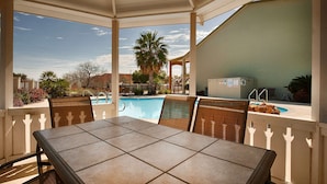 Un patio cubierto con piscina, mobiliario exterior y vistas del entorno.