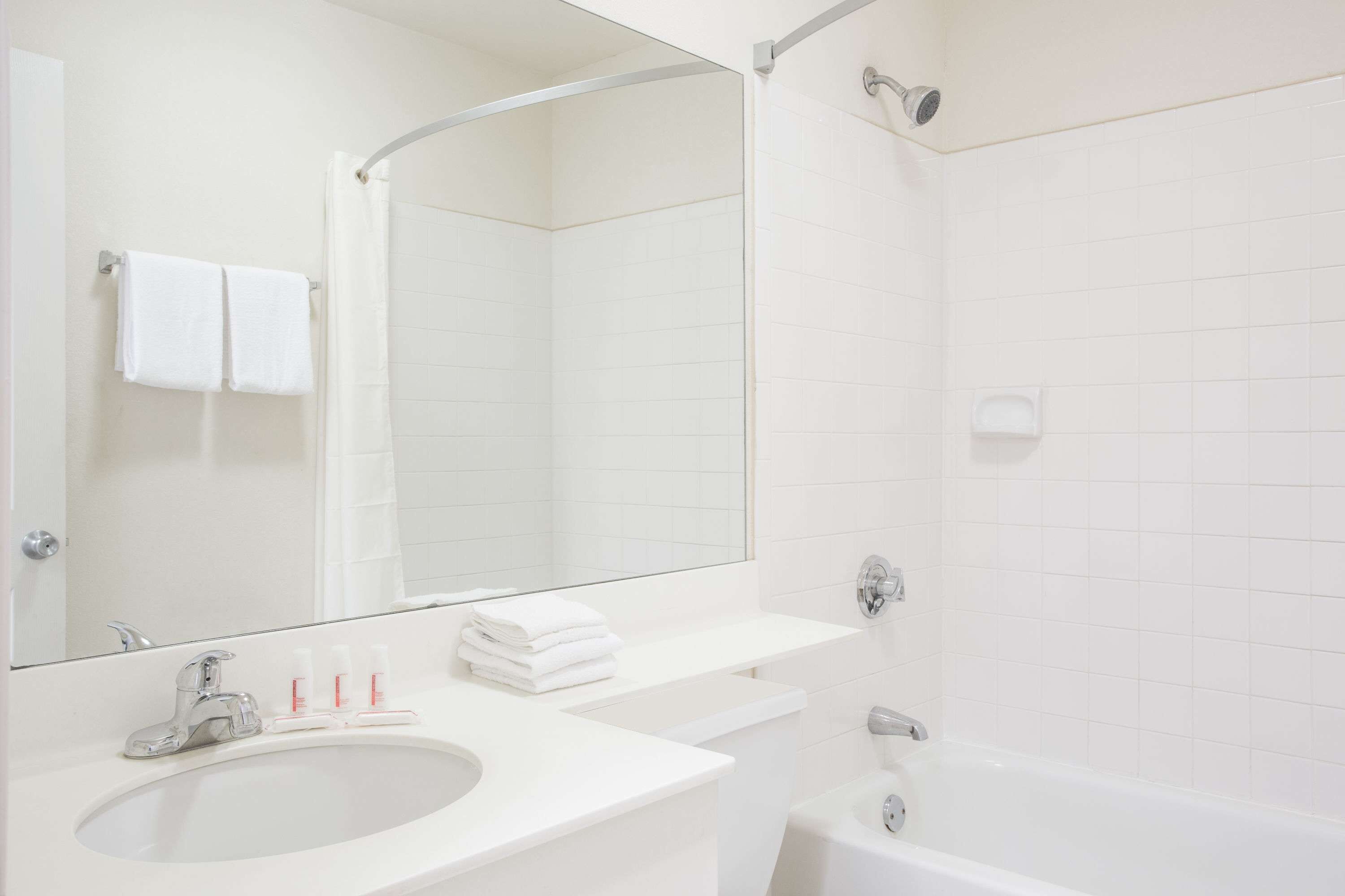Un baño moderno con lavamanos, espejo y bañera blancos.