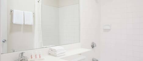 A modern bathroom with a white sink, mirror, and bathtub.
