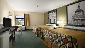 Une chambre d’hôtel avec deux lits, un bureau, une chaise, un téléviseur et de grandes photos encadrées représentant des bâtiments.