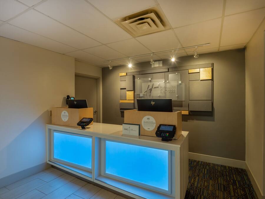 A reception area with a modern design, featuring a reception desk with a digital display and a sign indicating the hotel name.