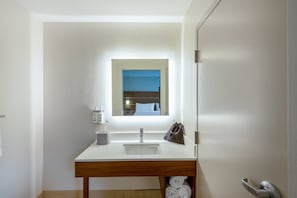 A modern bathroom with a white sink, wooden vanity, a mirror, and a towel rack. - Holiday Inn Express Vermilion by IHG (Vermilion)