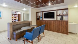 A modern waiting area with a sofa, chairs, a small table, and a TV. - Holiday Inn Express Vermilion by IHG (Vermilion)