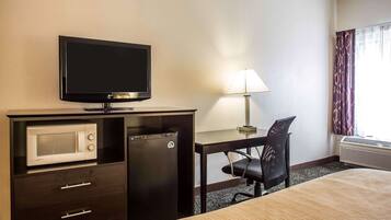 Habitación de hotel con cama, escritorio con silla, televisor, microondas y aire acondicionado.