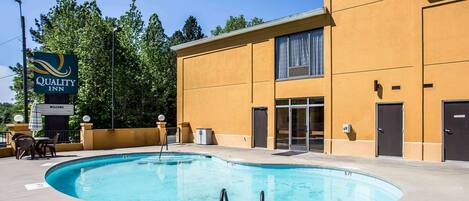 Un hotel con piscina, un cartel de 'Quality Inn' y un letrero de 'Welcome'.
