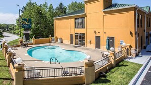 A hotel with a swimming pool, outdoor seating, and a sign reading "Quality Inn".