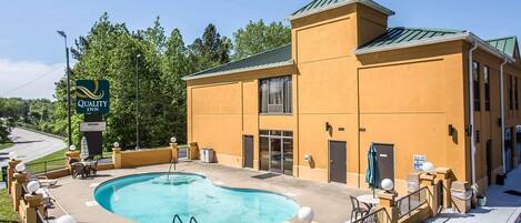 A hotel with a swimming pool, outdoor seating, and a sign reading "Quality Inn".