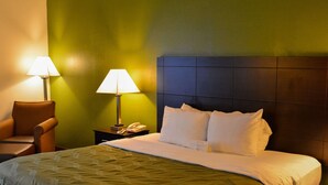A hotel room with a bed, two bedside lamps, a chair, and a nightstand with a phone.