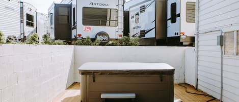 Un bain à remous avec des marches, situé dans un jardin, entouré d’une clôture blanche et d’une terrasse en bois.