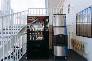 Una macchina automatica con etichetta 'COLD DRINKS' e un erogatore d'acqua in un contesto commerciale.