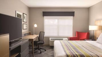 Une chambre d’hôtel avec un lit, un bureau, une chaise et une fenêtre avec des stores.