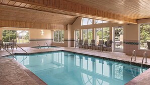 An indoor swimming pool with wooden ceiling beams, tiled walls, and large windows offering views of the outdoors. - Country Inn & Suites by Radisson, Madison, WI (Madison)