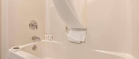 Eine weiße Badewanne mit Duschvorhang, Handtuch und Seifenschale.
