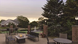 An outdoor patio with a fire pit, seating, and a view of a residential area. - Country Inn & Suites by Radisson, Madison, WI (Madison)
