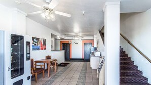 A hotel lobby with a dining area, a refrigerator, a staircase, and a ceiling fan. - Motel 6 Moriarty, NM (Moriarty)