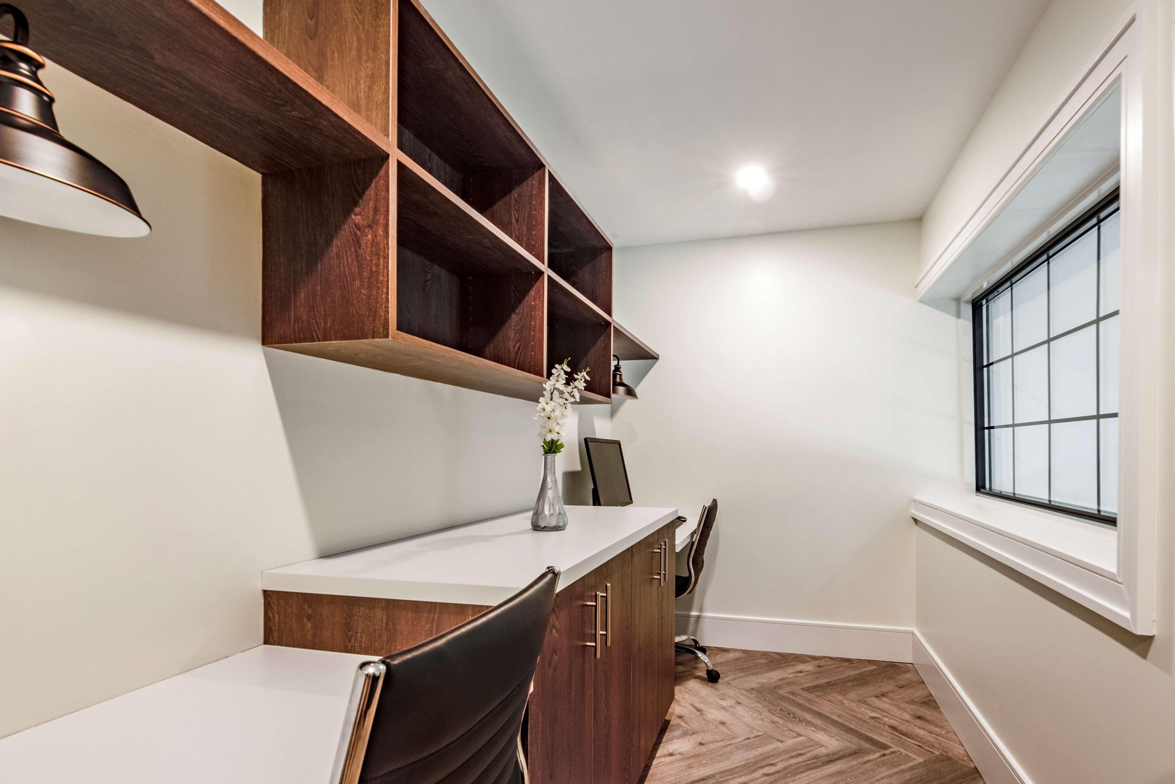 A small, well-lit room with a desk, chair, and shelves.