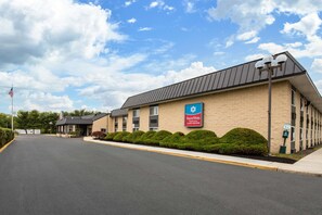 A SureStay by Best Western hotel with a brick facade, a parking lot, and a clear sky. - SureStay Plus Hotel by Best Western McGuire AFB Jackson (Cookstown)