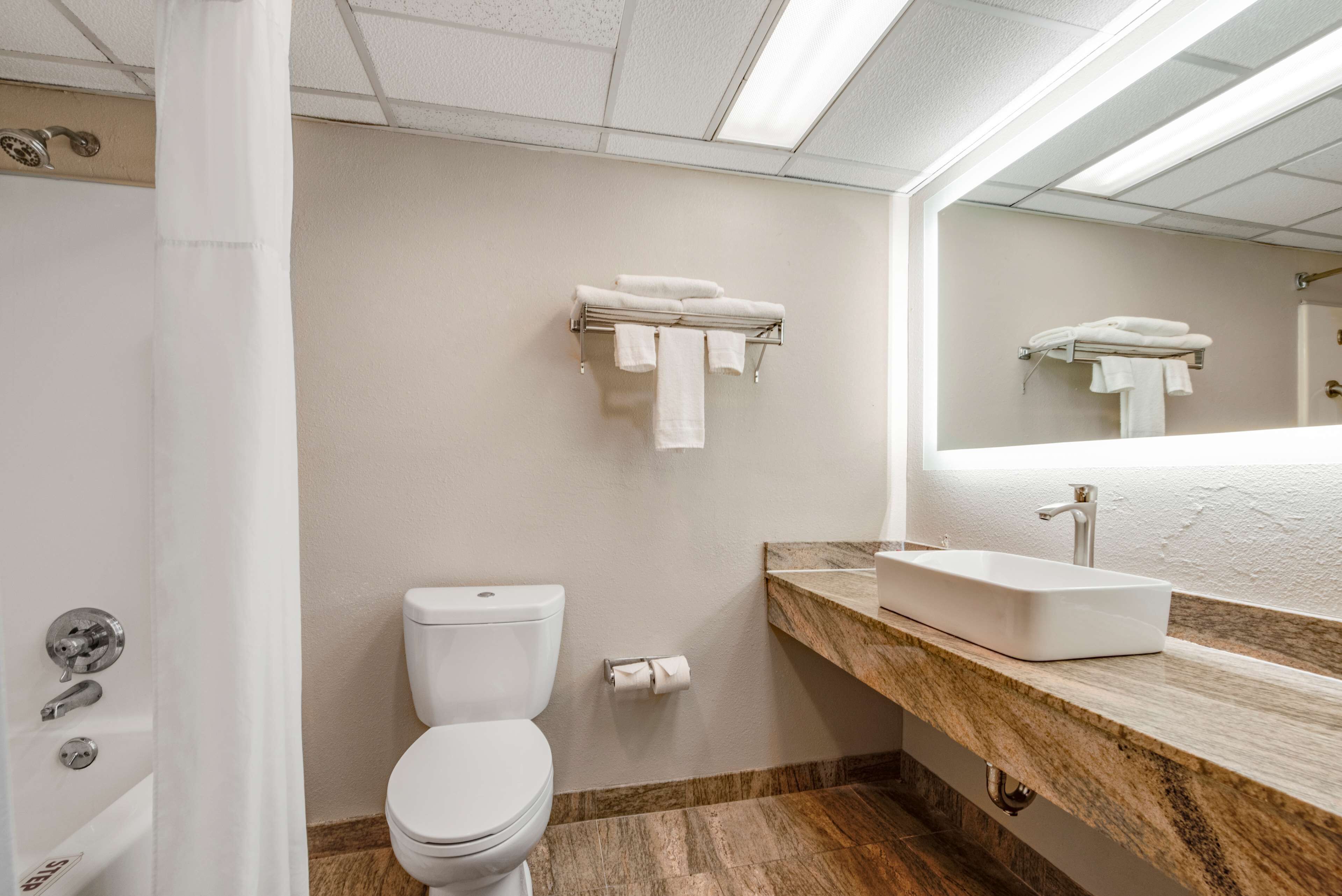 Un baño con inodoro, lavamanos y perchero para toallas.