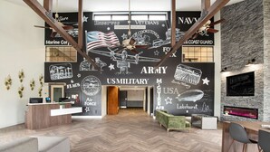 A reception area with a herringbone floor, wooden reception desk, and a wall decorated with military-themed murals. - SureStay Plus Hotel by Best Western McGuire AFB Jackson (Cookstown)