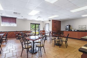 A spacious dining area with multiple tables and chairs, a counter with a cash register, and a view of the outdoors through a window. - SureStay Plus Hotel by Best Western McGuire AFB Jackson (Cookstown)