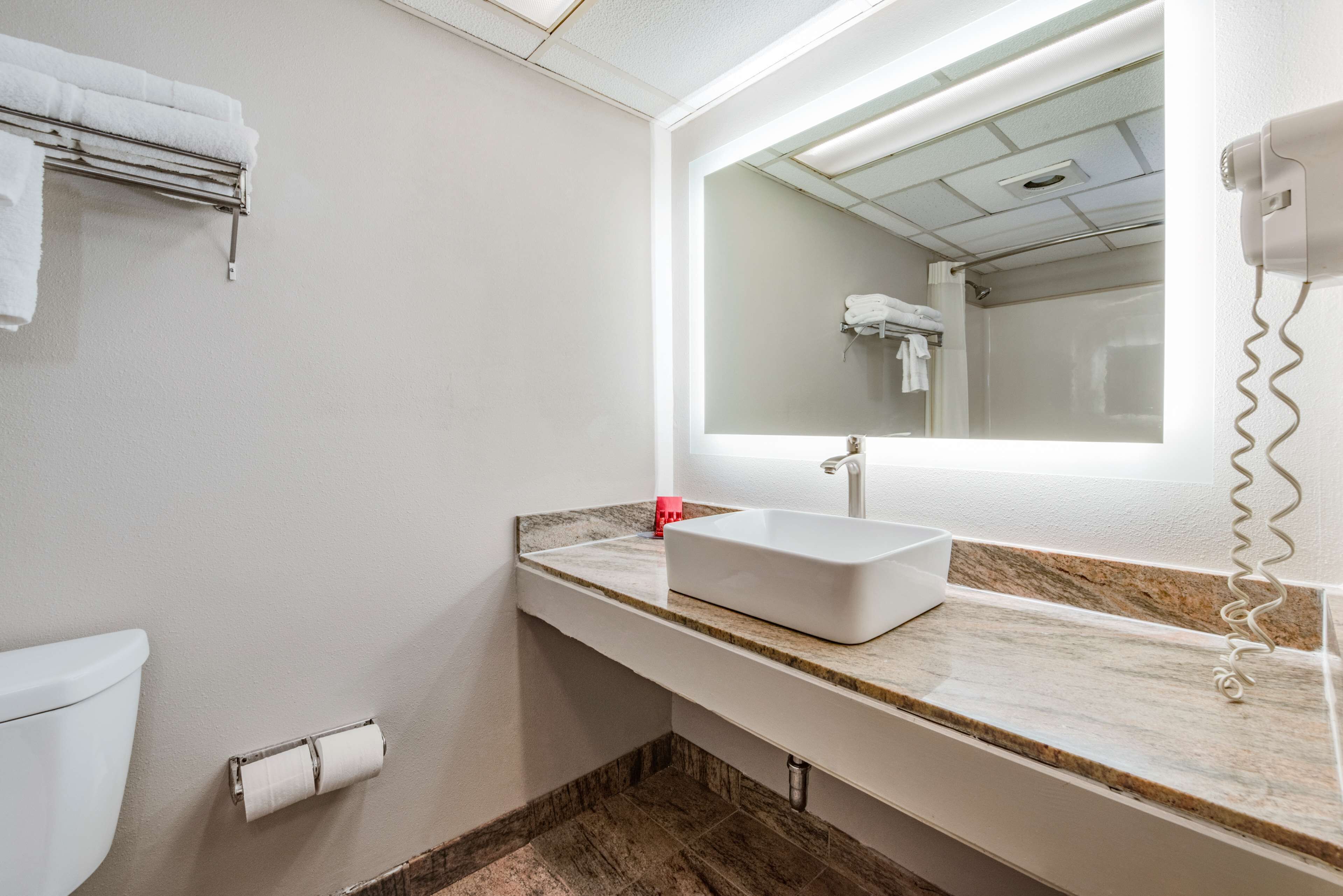 A bathroom with a white sink, a mirror, and a towel rack.