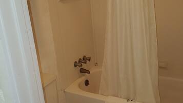 A bathroom with a bathtub, shower, toilet, and a towel rack with towels.